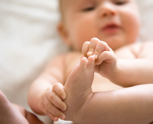 bebe se toma su pies con su manos